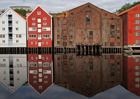 Wide panoramic view of old colorful wooden houses with reflections in river Nidelva in the Brygge district in Trondheim, Norwayの写真素材