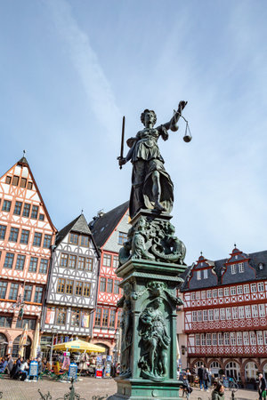 Frankfurt, Germany - March 28, 2023: Lady justice at Frankfurt Roemer with old half timbered houses in background.のeditorial素材