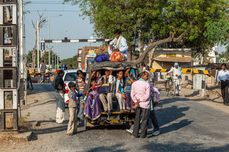 Fathepur Sikri, India - November 16, 2011: people in an overloaded Mini bus or rickshaw waiting in a queue for the passing train..のeditorial素材