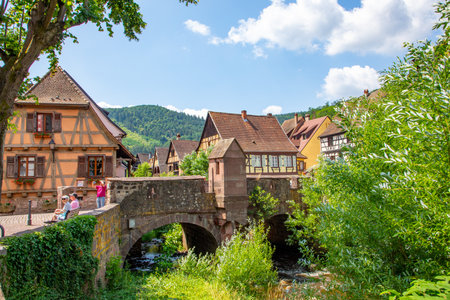 Kaysersberg, France - June 23, 2023: A picturesque colorful street of half-timber buildings with shops and cafes in the village of Kaysersberg in Vosges region.のeditorial素材
