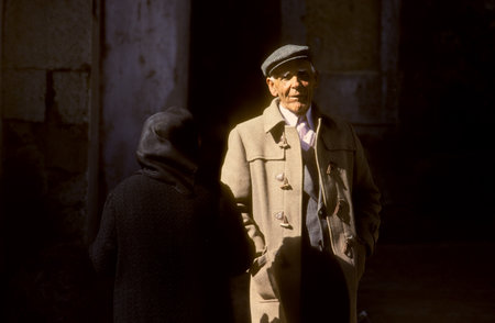 Lisbon, Portugal - July 4, 1992: portrait of old man in camelhair suit and backside of old lady in...
