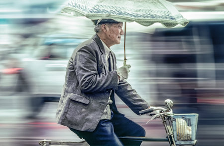 Beijing, China - August 1, 1982: old man rides his bicycle with umbrella in his arm. I 1982 bicycle was for more than 95 percent of chinese people the way for transportation even in Beijing.のeditorial素材