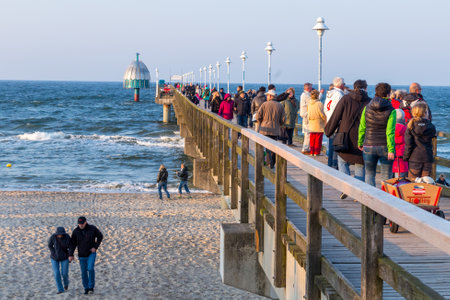 Zinnowitz, Germany - April 19, 2014: People enjoy walking at the beach and on the wooden pier in...