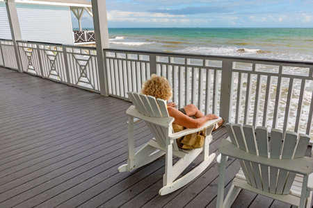 Woman enjoys the view from an old Victorian balcony to the colorful sea of Mexico in Galveston,...