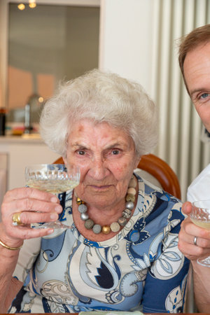 attractive elderly lady with a glass of sparkling wine drinks a toast to her health and ageの写真素材