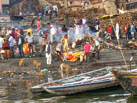 Varanasi, India - February 24, 2024: People prepare a dead person decorated with colorful dress and flowers for the burial ceremony at river Ganges in Varanasi.のeditorial素材