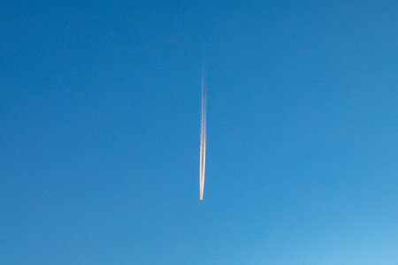 Contrail of an aircraft in morning light at blue skyの写真素材