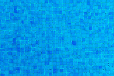 pattern of blue pool tiles under water with textured water surface gives a harmonious backgroundの写真素材