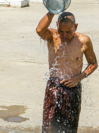 Inle Lake, Myanmar - April 29, 2007: Monk has a shower from a zinc bucket in early morning.