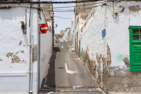 narrow street with rotten white painted brick walls in the old town of Arrecife in midday sun, Lanzarote, Spainの写真素材