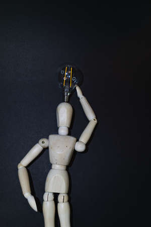 Mannequin Wood Figure carrying an incandescent light bulb. New idea concept. black backgroundの写真素材
