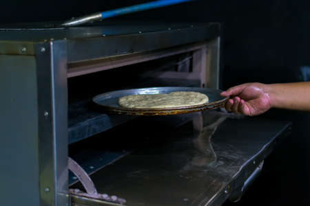 putting an artisanal pizza in the ovenの写真素材