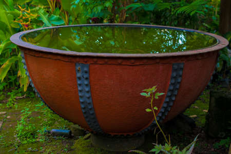 old large iron bowl used as a water container for plantsの写真素材