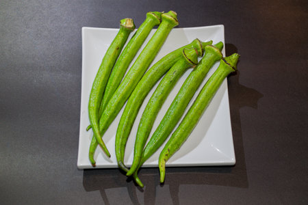 Fresh okra on a white plate on a black background, stock photoの写真素材