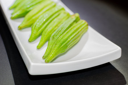 Fresh okra on a white plate on a black background. Close up.の写真素材