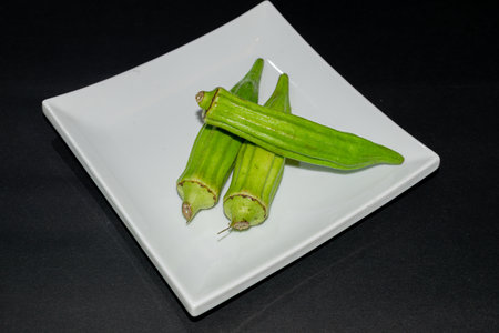 Fresh okra on a white plate. Isolated on black background.の写真素材