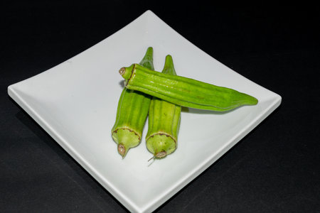 Fresh okra on white plate isolated on black background, stock photoの写真素材
