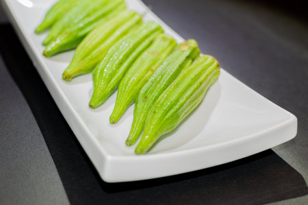 Close up of fresh okra on white plate on black background.の写真素材