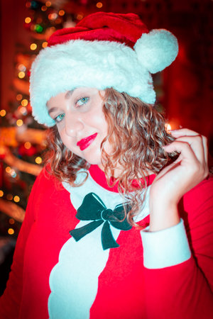 Portrait of beautiful young woman in Santa Claus hat on Christmas backgroundの写真素材