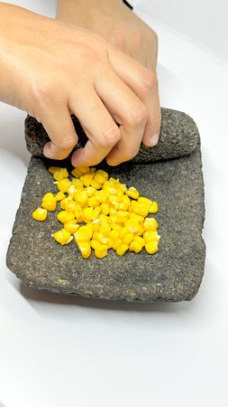 Women's hands grinding corn on a stone called a metate, which was used by ancient civilizations.