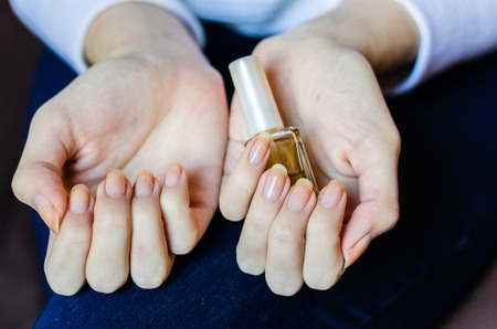 Woman with long fingers and nails applying transparent nail base