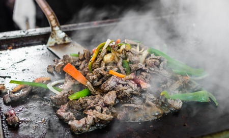 Chef at a street food market frying beef and vegetables for tacosの写真素材