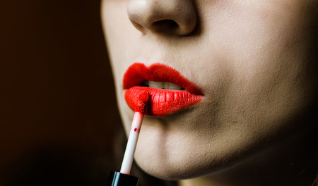 Young woman with smooth skin applying red lipstickの写真素材