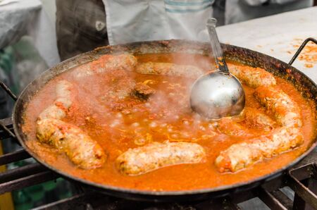 Cooking traditional Italian stew with sausages at a street food marketの写真素材
