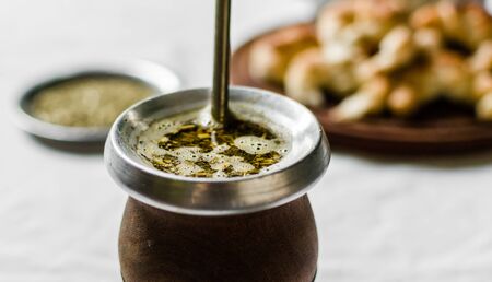 Yerba mate tea, croissants on a wooden board, and kettle on white backgroundの写真素材