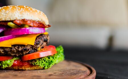Burger on a wooden table against black backgroundの写真素材