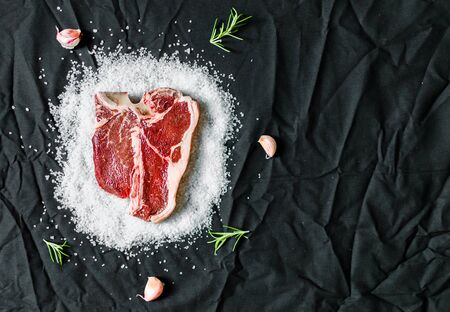 T bone steak of beef meat against black backgroundの写真素材