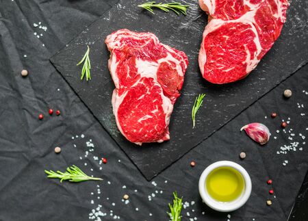 Rib eye beef cow steak meat with spices and herbs against black backgroundの写真素材