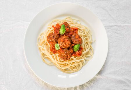 Spaghetti pasta with meatballs in tomato sauce and basil leaves