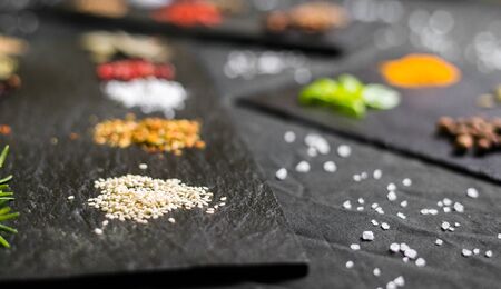 Large selection of different colorful contrast spices and seeds on slateの写真素材