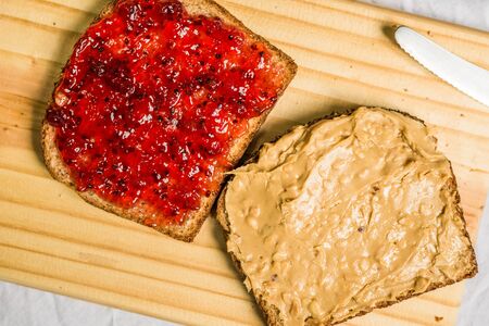 Peanut butter and jelly sandwich on a wooden board against white backgroundの写真素材