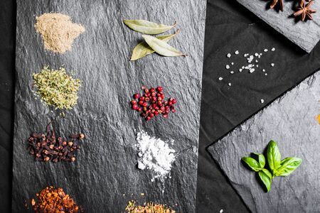 Large selection of different colorful contrast spices and seeds on slateの写真素材