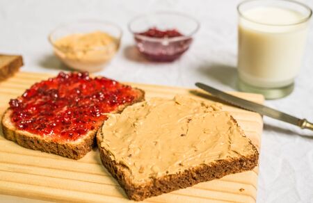 Peanut butter and jelly sandwich on a wooden board against white backgroundの写真素材