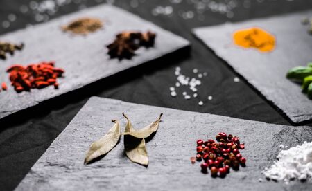 Large selection of different colorful contrast spices and seeds on slateの写真素材