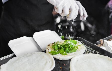 Chef preparing tortilla with arugula, parma, and cheese at street food marketの写真素材