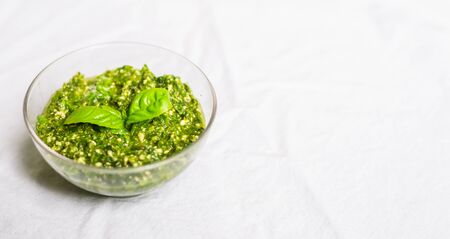 Basil and cheese pesto on a wooden board against white backgroundの写真素材