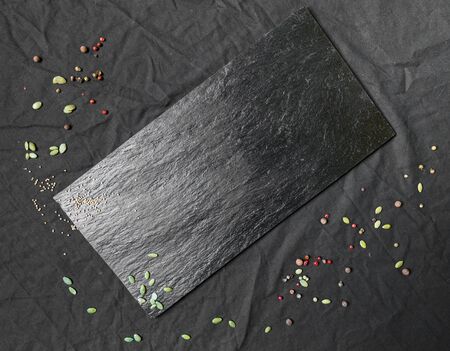 Contrast food background in black with slate serving board, seeds, and spices.