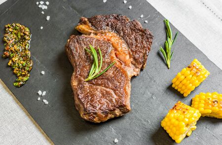 Grilled rib eye beef steak meat with chimichurri sauce against black backgroundの写真素材