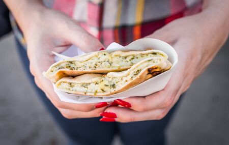 Eating a khachapuri sandwich with grilled melted cheese at a street food market.の写真素材