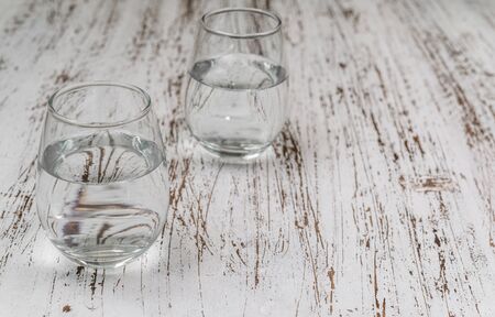 A glass of still mineral drinking water against white wood background.の写真素材