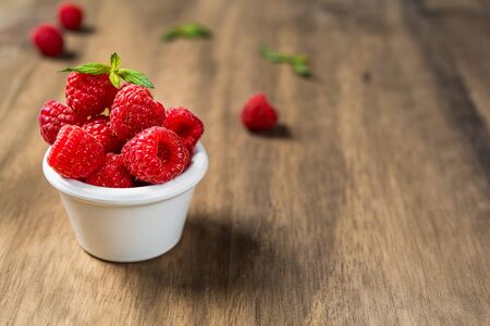 Fresh colorful organic raspberry fruit against wooden backgroundの写真素材