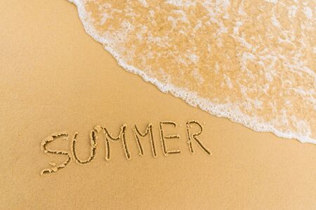 Ocean sea waves running over the caption summer written on the sandの写真素材