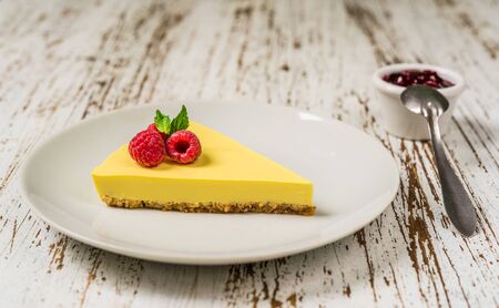 Lemon cheesecake with raspberries, mint, and jam against white wood backgroundの写真素材
