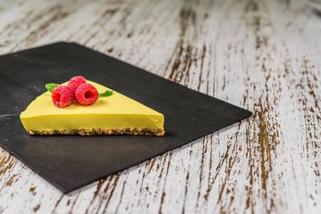Lemon cheesecake with raspberries, mint, and jam against white wood backgroundの写真素材