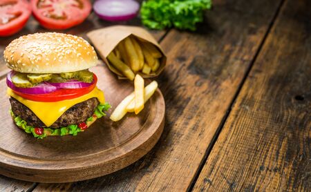 Cheese burger and french fries against wooden background. Tasty fast foodの写真素材