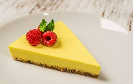 Lemon cheesecake with raspberries, mint, and jam against white wood backgroundの写真素材